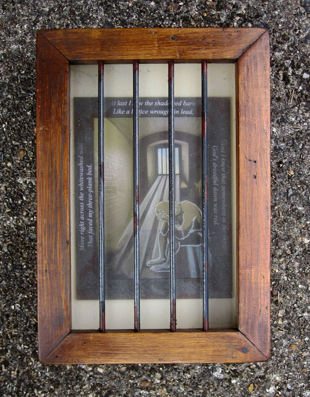 Wooden box with bars and the image of a prisoner inside