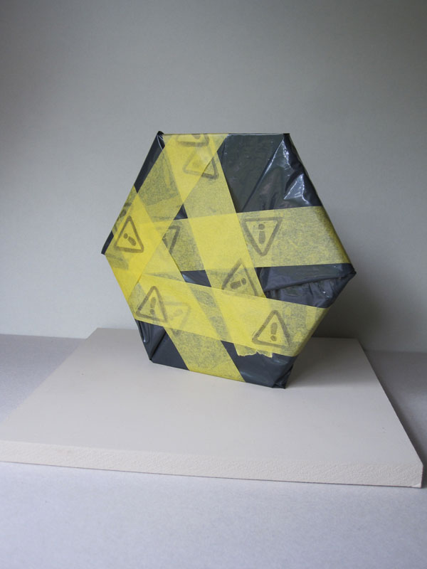 A hexagon wrapped in black plastic and hazard tape